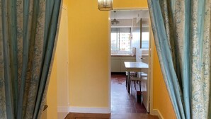Un couloir doté d’un plancher en bois, de murs jaunes et donnant sur un coin repas avec une table et des chaises.