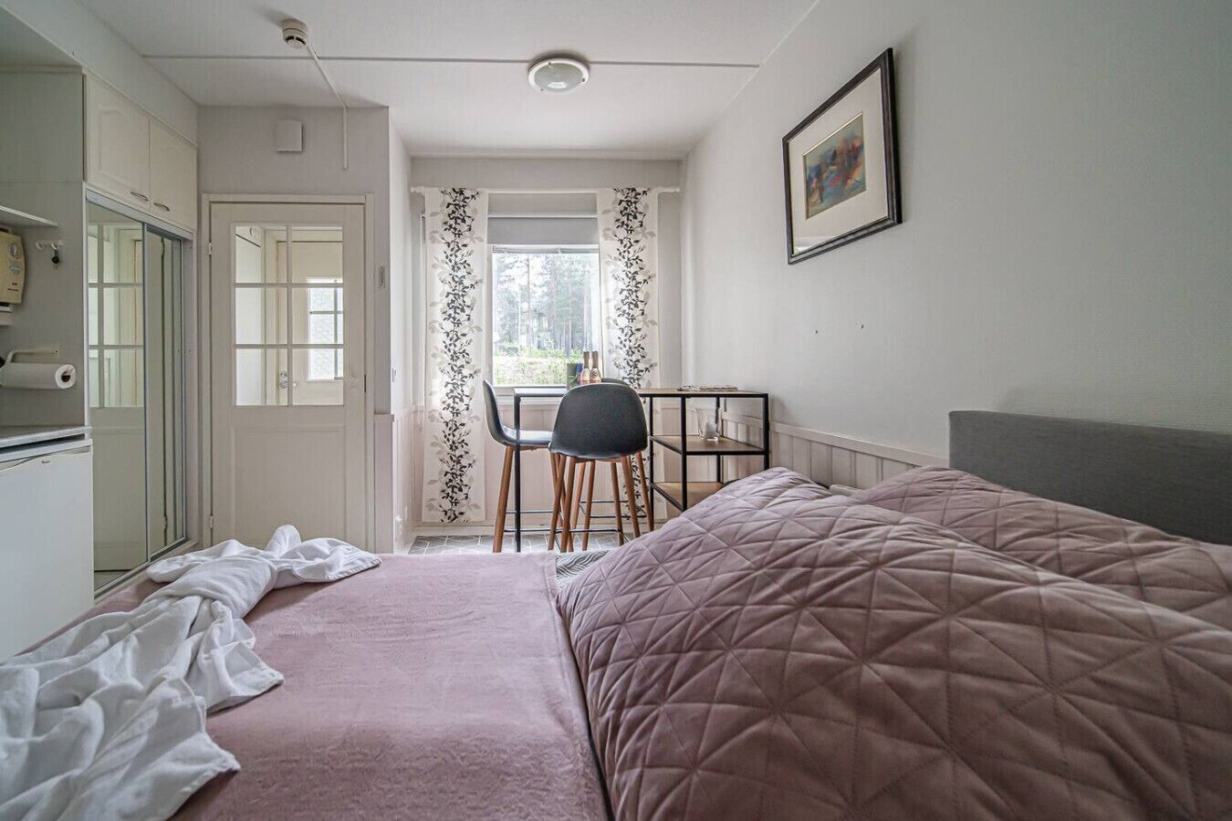 Een slaapkamer met een bed, een bureau en een stoel.