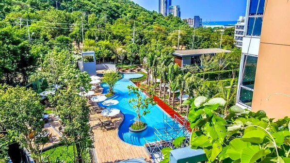 Une piscine au design sinueux, entourée d’une végétation luxuriante et offrant une vue sur le panorama urbain.