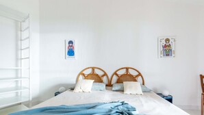A bedroom with a bed, two wooden headboards, a blue blanket, a white wall, and a small nightstand with a lamp. - Domus Sole (Campulongu)