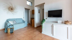 A living room with a sofa, a television, a cabinet, and a window. - Domus Sole (Campulongu)