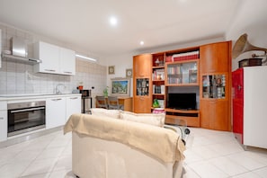 Una cocina moderna con armarios blancos, horno empotrado y un comedor con mesa y sillas.
