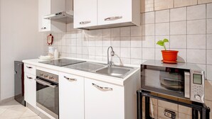 Moderni keittiö, jossa on sisäänrakennettu uuni, mikroaaltouuni ja ruostumattomasta teräksestä valmistettu pesuallas.