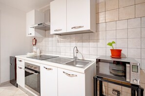 Una cocina moderna con horno integrado, microondas y pileta de acero inoxidable.
