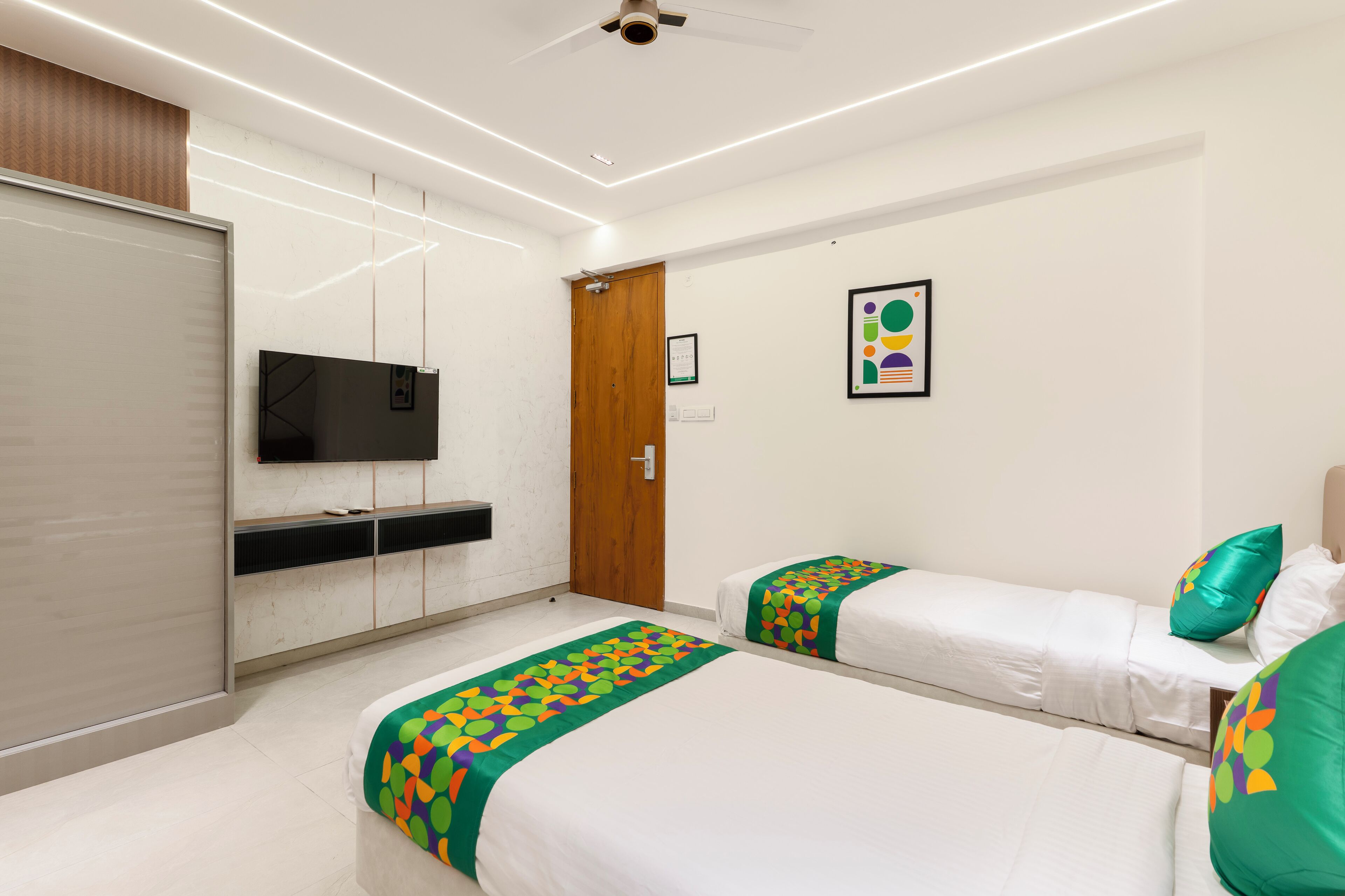 A hotel room with two beds, a television, a wardrobe, and a door.