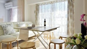 A modern living room with a sofa, a dining table, and a TV. - Hema Homestay Nihonbashi (Osaka)