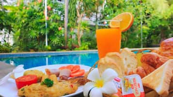 A breakfast setting with a plate of food, a glass of orange juice, and a basket of bread.
