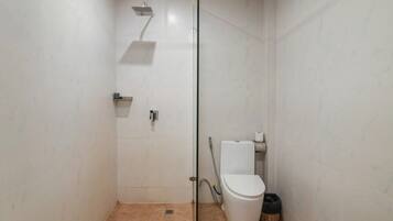 Une petite salle de bain moderne avec une douche à parois de verre, des toilettes et une poubelle.