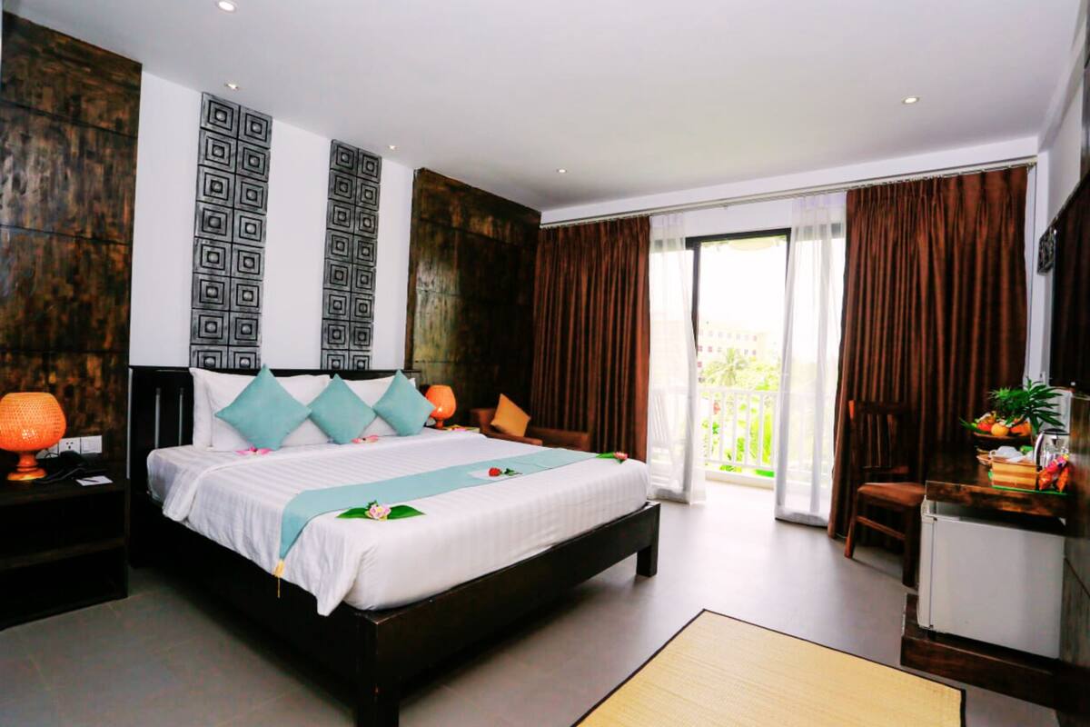 A modern hotel room with a large bed, a desk, and a balcony.