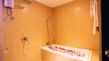 A bathroom with a bathtub filled with rose petals, a showerhead, and a towel rack.