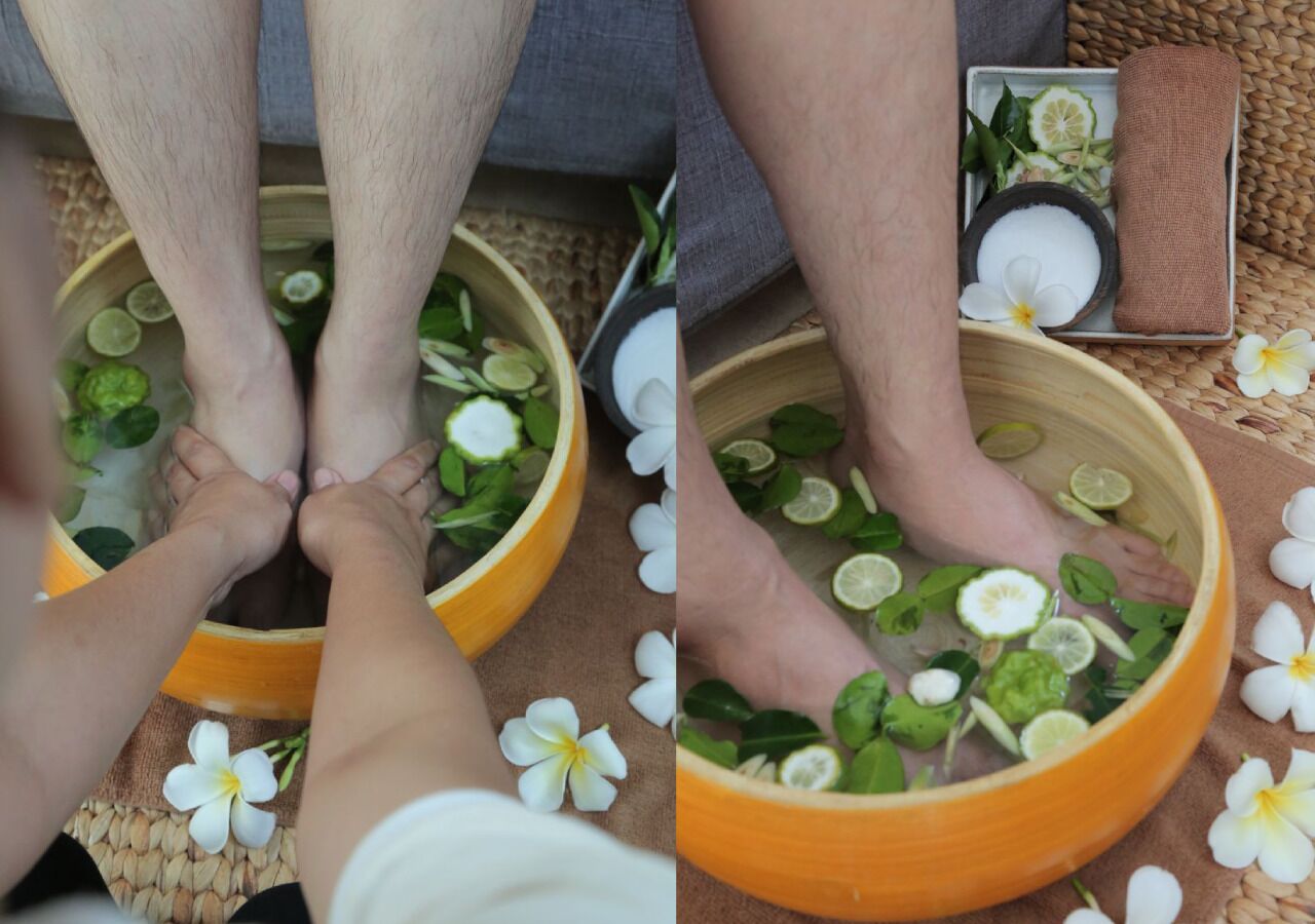A foot soak with lime slices and leaves, a small bowl of salt, and a cloth.