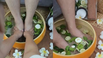 A foot soak with lime slices and leaves, a small bowl of salt, and a cloth.