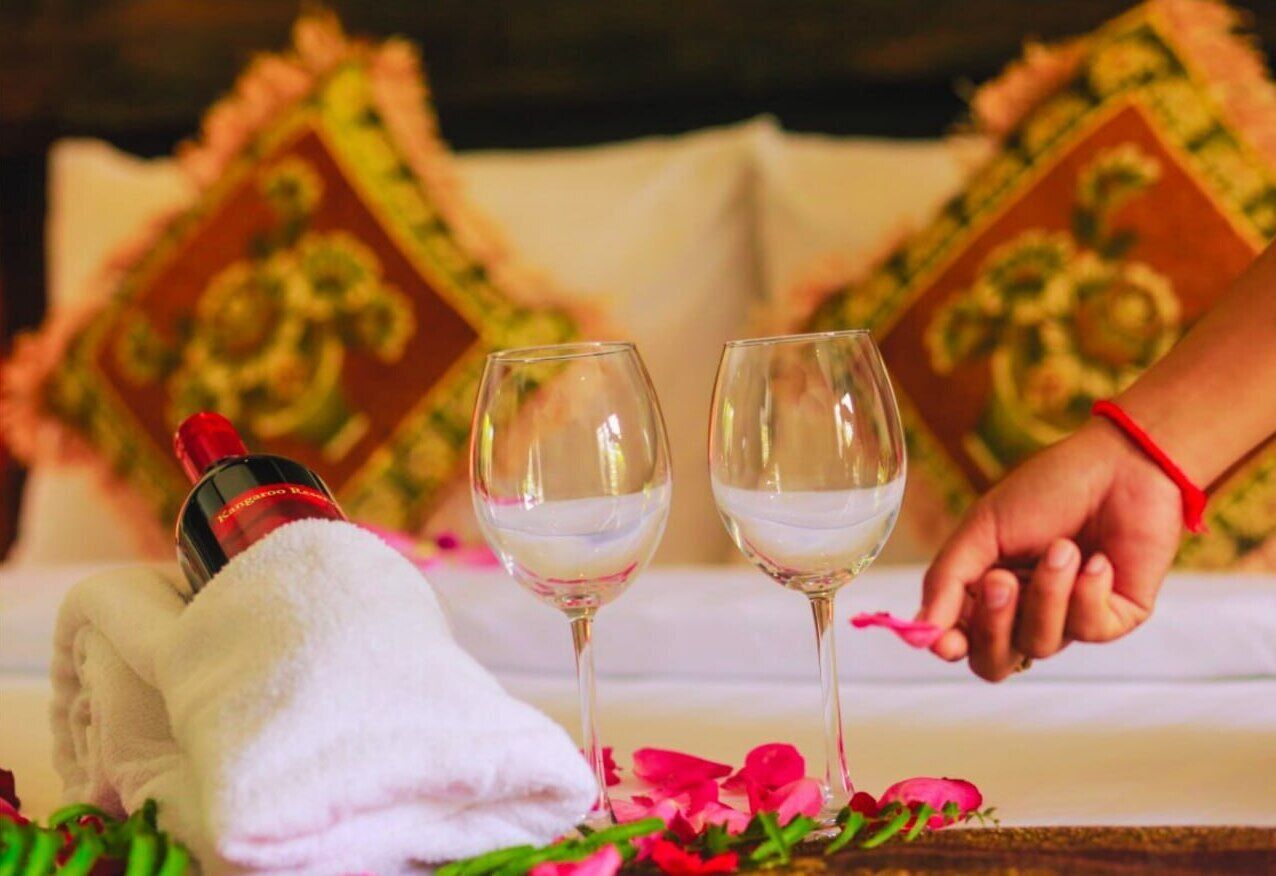 A bed with a white towel and two glasses of water, a bottle of water, and a hand holding a pink object.