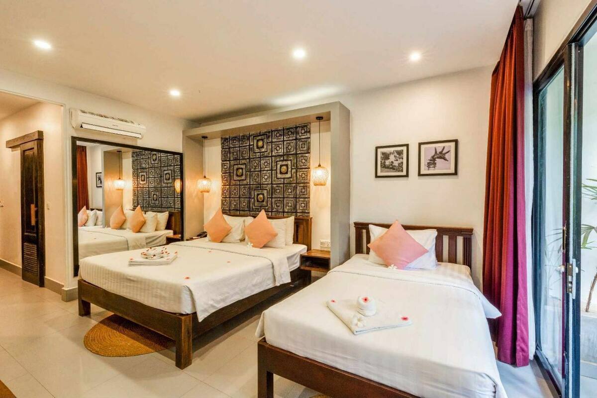 A hotel room with two beds, a decorative wall, and a large window with curtains.