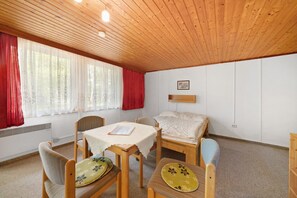 A room with a wooden ceiling, a bed, a table with chairs, and a window with curtains. - Bungalow '5 - Kimbucht' with Private Terrace and Shared Garden (Waldhufen)