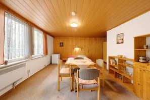 Une pièce aux murs en bois, avec une table à manger et des chaises, un radiateur et une bibliothèque.