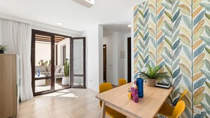 Uma área de refeições moderna com mesa de madeira, cadeiras amarelas e papel de parede estampado.