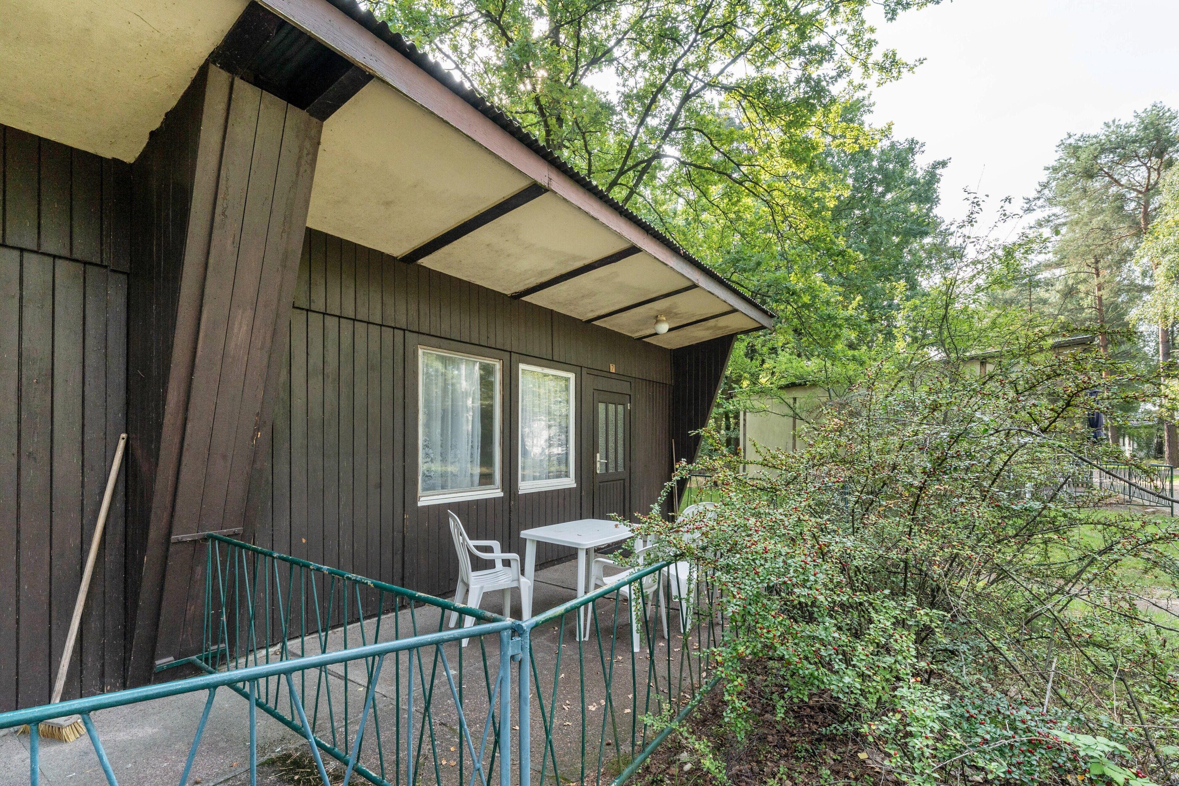 A wooden building with a covered patio, a table, and chairs.