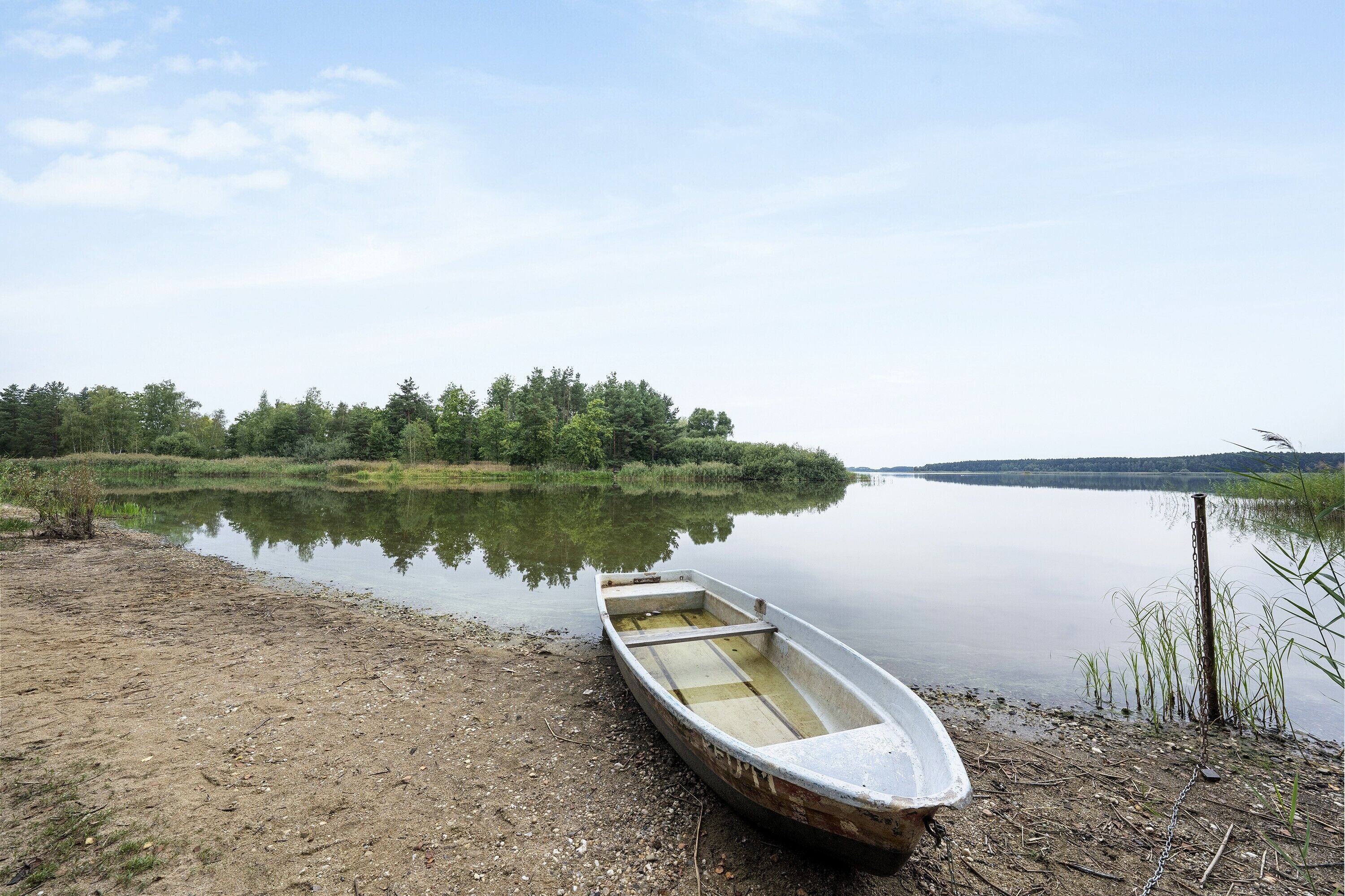 A small boat on a calm lake with a forested shoreline.