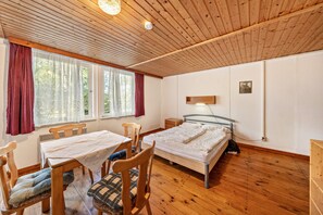 Une pièce avec un plafond en bois, un lit, une table avec des chaises et une fenêtre avec des rideaux.