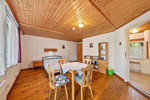 Un plafond en bois, un lit, une table avec des chaises, une fenêtre et une porte.