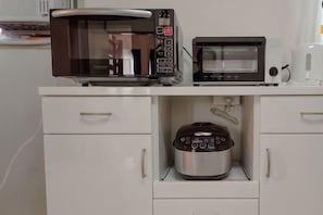 Et køkken med mikrobølgeovn, brødrister og slow cooker.