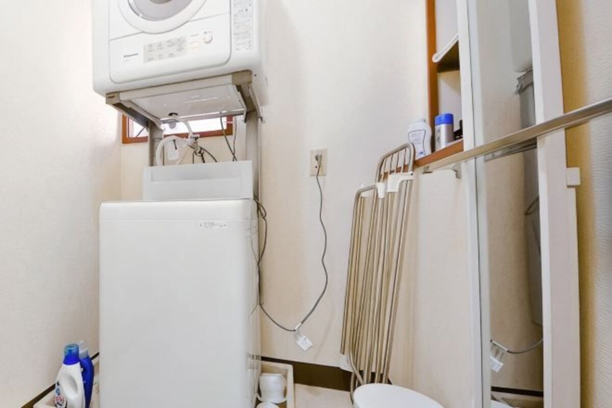 A bathroom with a white washing machine, a radiator, and a toilet.