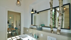 A modern bathroom with a large mirror, a sink, and a chair.