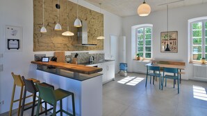 A modern kitchen with a central island, bar stools, and pendant lighting.