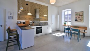 A modern kitchen with a central island, pendant lighting, and a dining area with a bench and chairs.
