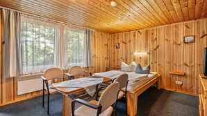 A wooden cabin room with a bed, table, chairs, and a television.