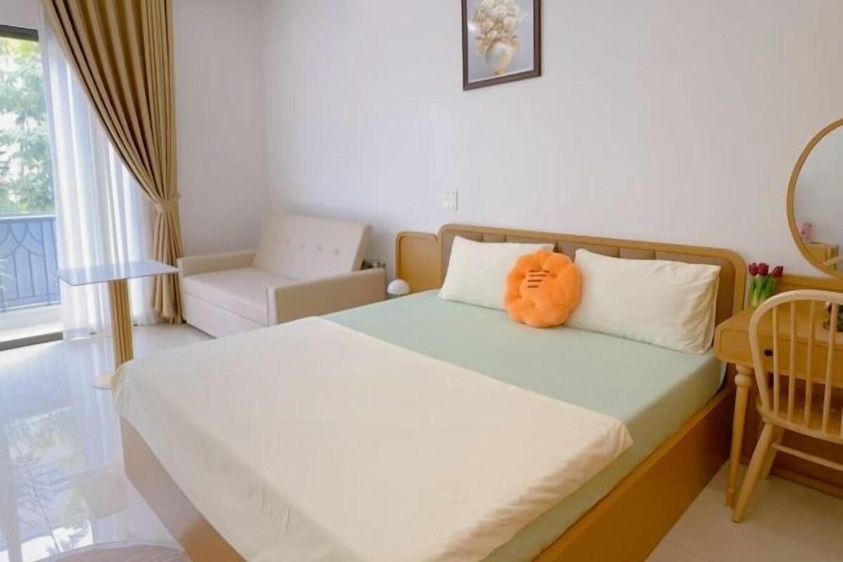 Une chambre à coucher avec un lit, une chaise, une table et une fenêtre avec des rideaux.