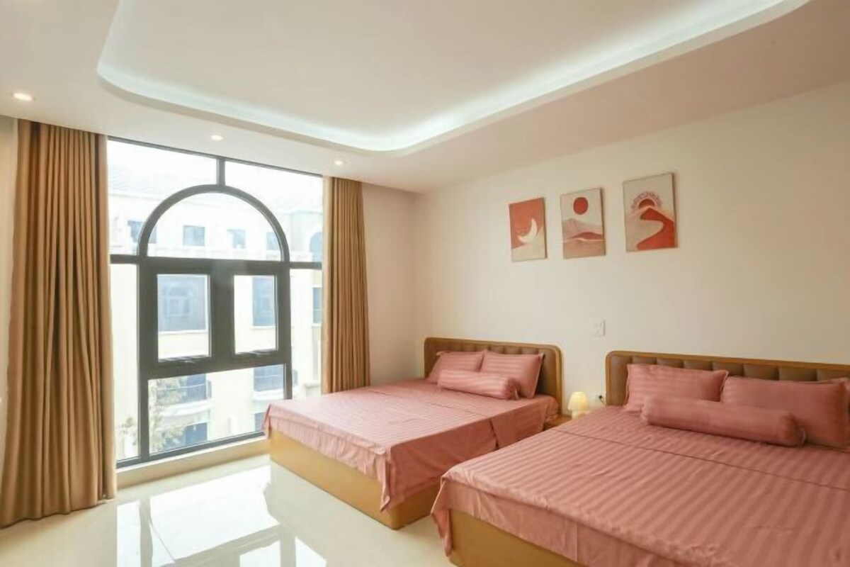 A hotel room with two beds, a large window, and artwork on the wall.
