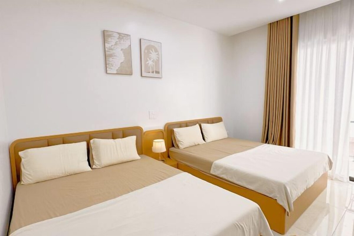 A hotel room with two beds, a nightstand, and a window with curtains.