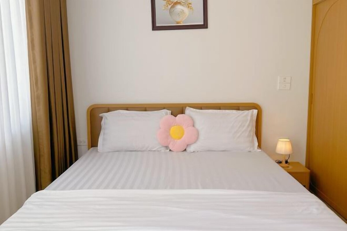 A neatly made bed with white linens and a single decorative pillow.