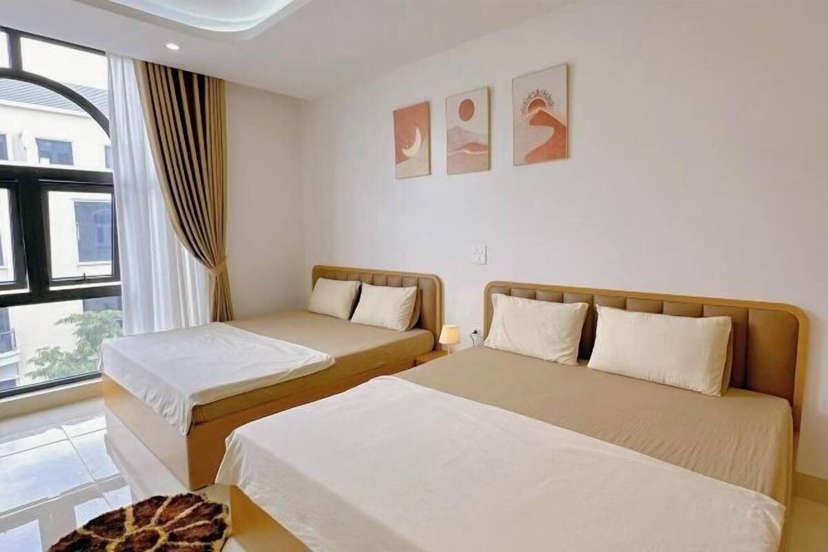 A hotel room with two beds, a window with curtains, and three wall art pieces.