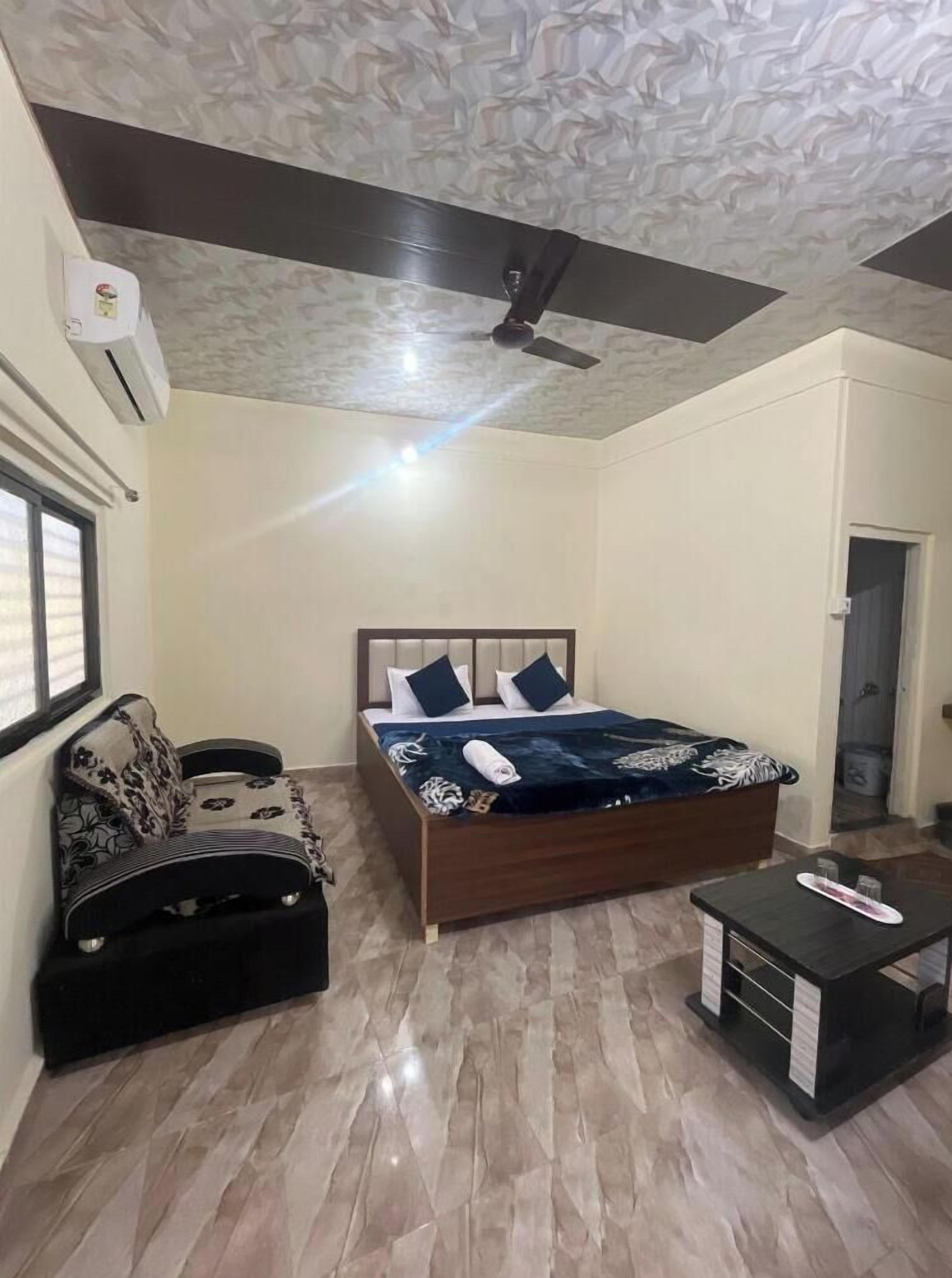 A bedroom with a bed, a sofa, a small table, and a ceiling fan.
