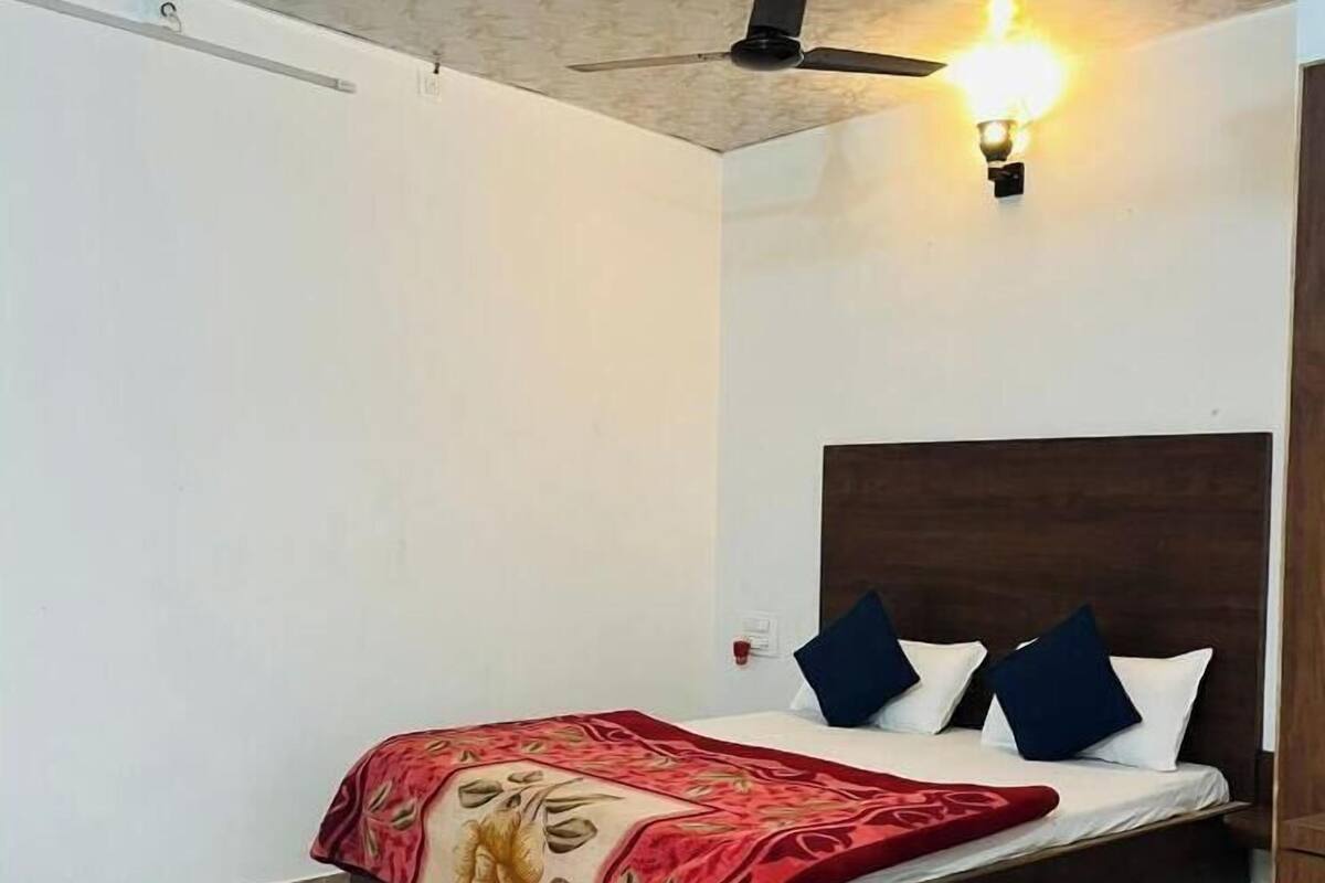 A bedroom with a bed, a ceiling fan, and a wall-mounted light fixture.
