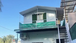 Un bâtiment à deux étages, doté d’un toit plat, d’un balcon à l’étage supérieur et d’un escalier menant à l’étage.