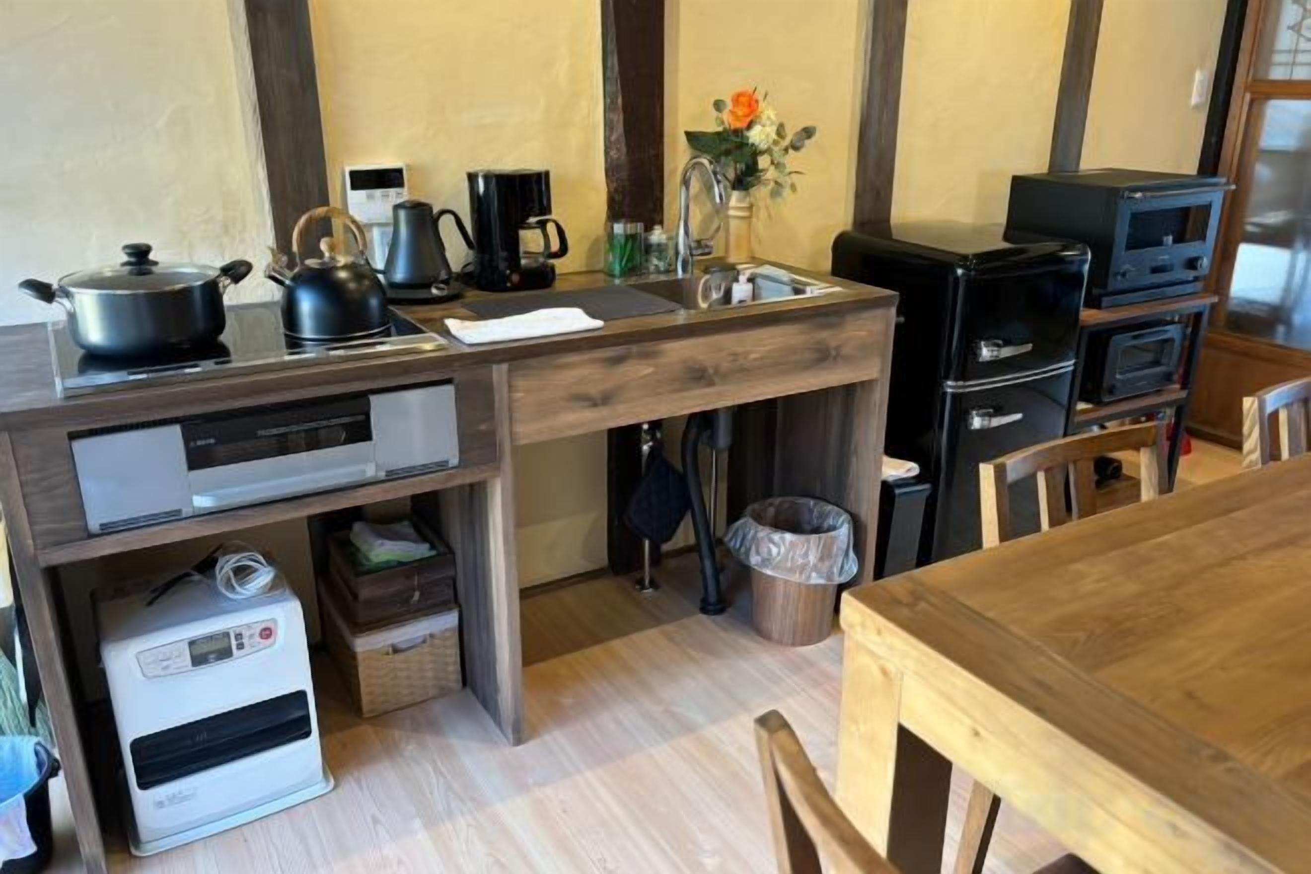 A compact kitchen with a wooden countertop, a stove, a sink, and a coffee maker.