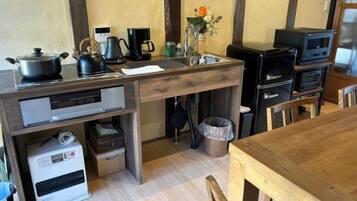 A compact kitchen with a wooden countertop, a stove, a sink, and a coffee maker.