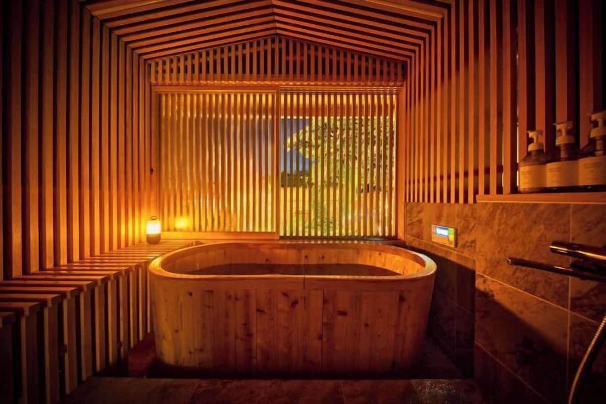 Puinen sauna, jossa on suuri amme, puiset lauteet ja ikkuna, josta on kaunis näkymä.