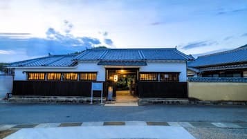 Un edifici japonès tradicional amb teulada de rajola, entrada central i un camí que condueix a la porta.