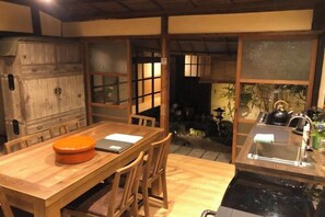 A traditional Japanese-style room with tatami flooring, a wooden table with a laptop, and a kitchen area with a kettle. - Tetsu-juro （former Ogunis residence） , Himeji Castles back parlor-like"400-year-old inn" (Fukusaki)