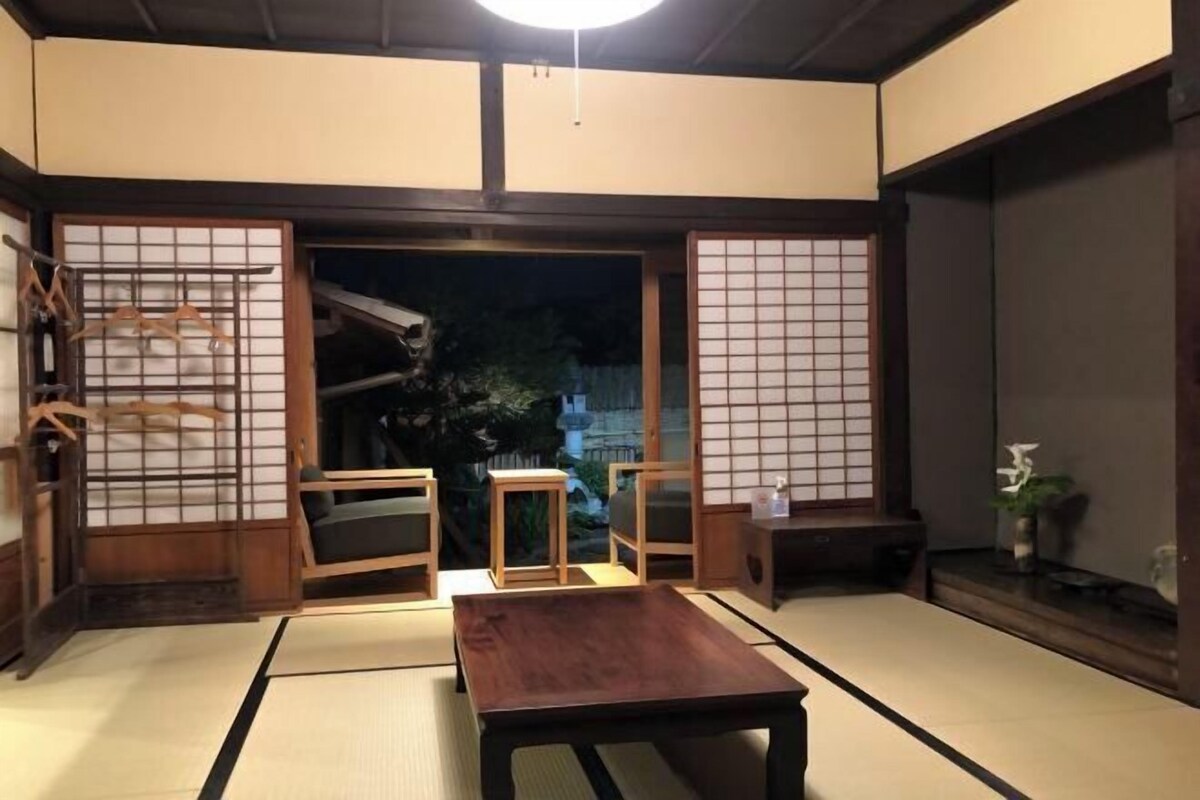 Una habitación tradicional japonesa con suelo de tatami, una mesa de madera baja y puertas correderas.