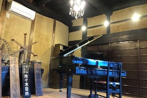 Una habitación con un piano de cola, una araña y una gran puerta de madera.