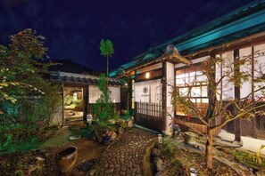 Ein traditionelles japanisches Gebäude mit Holzfassade, einem Kiesweg und einem gepflegten Garten.