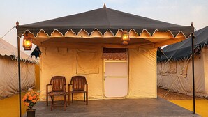 A single-story building with a flat roof, a front door, and two wooden chairs outside. - Stayguru Patgar Tent (Bhuj)