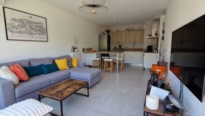 Een moderne woonkamer met een bank, salontafel en een eethoek met krukken.