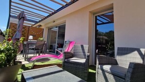 Een terras buiten met rieten meubels, een pergola en een bloempot.
